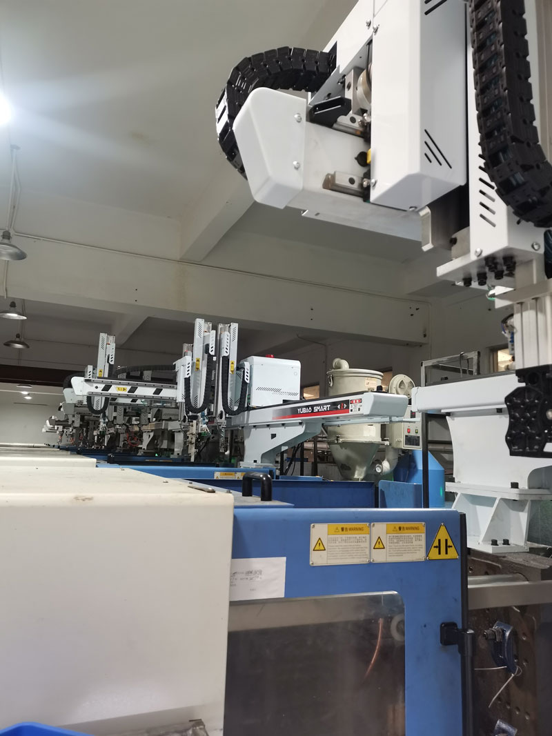 Close-up view of Yubao Smart traverse robot arms in injection molding production workshop
